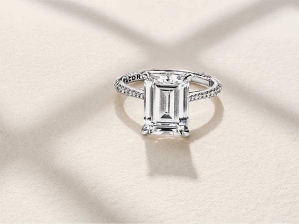 An emerald cut diamond ring with pavé diamonds and a hidden halo.
