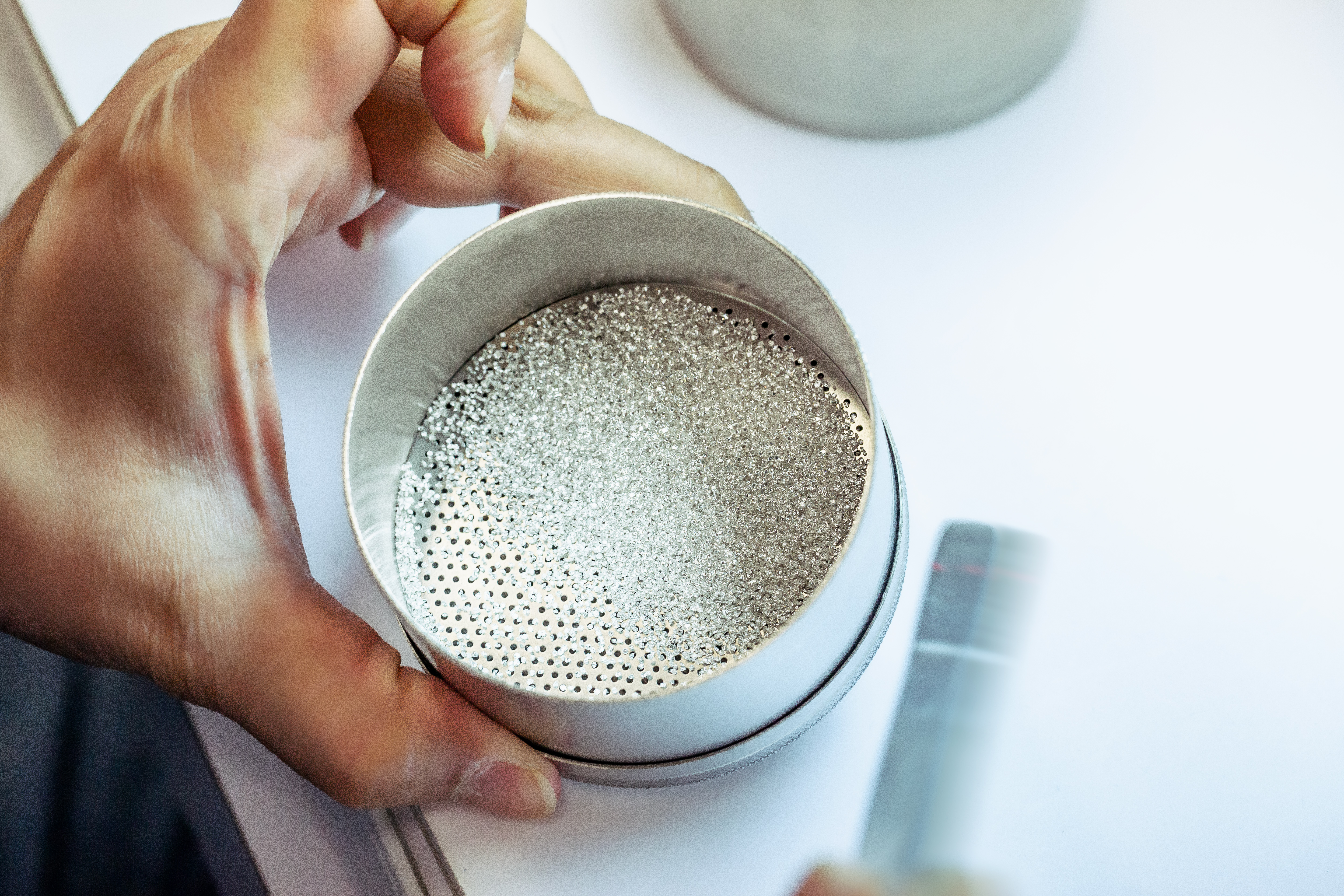 Sorting diamonds with a sieve for a diamond ring. 
